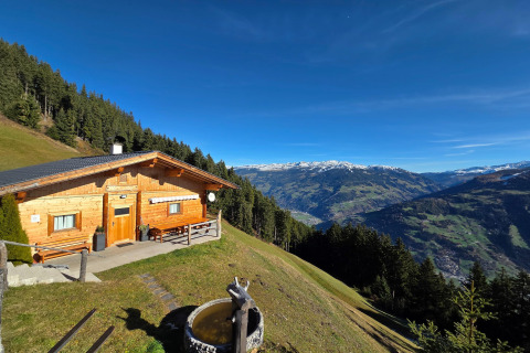 Udsigt over bjerge og skov fra Almhütte Nase-chalet i Østrig under en klar blå himmel.