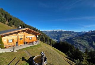 Udsigt over bjerge og skov fra Almhütte Nase-chalet i Østrig under en klar blå himmel.