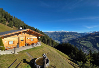 Udsigt over bjergene fra Almhütte Nase-chalet i Østrig, med træhytte, skov og sneklædte tinder.