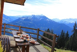 Udendørs morgenmad ved Almhütte Nase-chalet med udsigt til de østrigske bjerge og en dal.