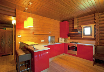 Cozy kitchen in Chalet Catharina im Brixental, Austria, featuring wooden walls and modern red cabinets.