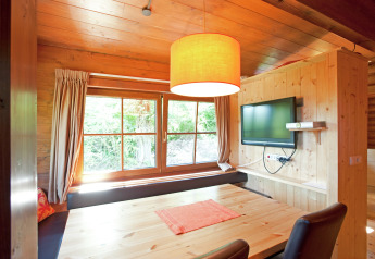 Cozy living space in Chalet «Catharina im Brixental» in Austria featuring wood decor, large windows and TV.