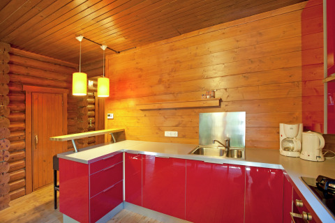 Modern wooden kitchen interior with red cabinets and pendant lights at Chalet Catharina in Austria.