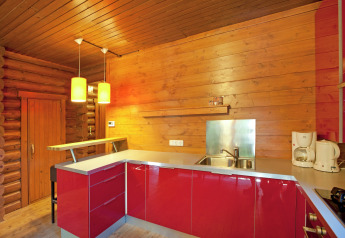 Modern wooden kitchen interior with red cabinets and pendant lights at Chalet Catharina in Austria.