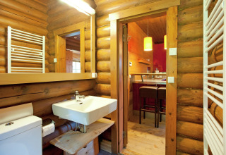 Bathroom with wooden log walls and modern fixtures at Chalet Catharina im Brixental, Austria.