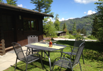 Outdoor seating at Chalet Catharina im Brixental with a mountain view, wine on table, sunny Austria day.