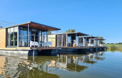 Moderne woonboten op het water in Denemarken, geschikt voor twee personen, met helderblauwe lucht.
