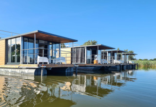 Moderne woonboten op het water in Denemarken, geschikt voor twee personen, met helderblauwe lucht.