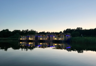 Huis op het water voor 2 personen in Denemarken bij schemer, sfeervol verlicht, weerspiegeld in stil water.