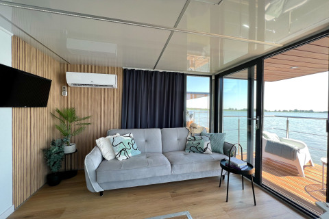 Woonkamer van woonboot 'House on the water for 2 people' met zetel en zicht op water in Denemarken.