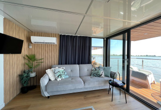 Woonkamer van woonboot 'House on the water for 2 people' met zetel en zicht op water in Denemarken.