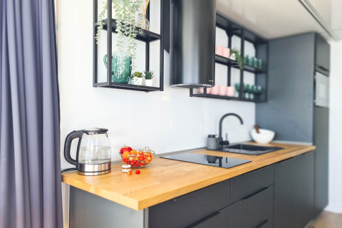 Moderne keuken op woonboot in Denemarken met houten blad, waterkoker en stijlvolle open planken.