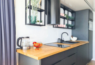 Moderne keuken op woonboot in Denemarken met houten blad, waterkoker en stijlvolle open planken.