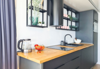 Modern kitchen on a Danish houseboat with wood countertop, electric kettle, and stylish open shelves.