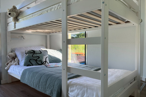 Modern houten stapelbed in een zonnige kamer op een Deense woonboot, uitzicht op natuur buiten.