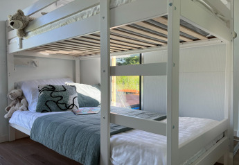 Modern houten stapelbed in een zonnige kamer op een Deense woonboot, uitzicht op natuur buiten.