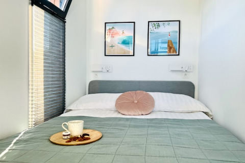 Cozy bedroom on a houseboat in Denmark, featuring a double bed, art on the wall, and a tray with coffee.