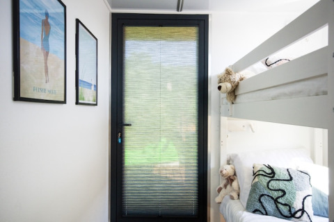Bright room on a houseboat in Denmark with bunk beds, stuffed animals, and framed pictures on the wall.