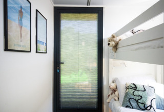 Bright room on a houseboat in Denmark with bunk beds, stuffed animals, and framed pictures on the wall.