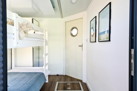 Kamer met stapelbed, blauw beddengoed, knuffel en maritieme decoratie in woonboot in Denemarken.