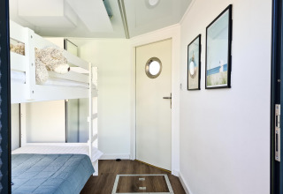 Room with bunk beds, blue bedding, stuffed animal and nautical decor inside houseboat in Denmark.