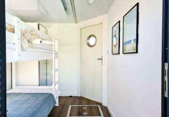 Room with bunk beds, blue bedding, stuffed animal and nautical decor inside houseboat in Denmark.