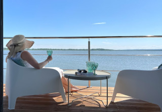 Woman relaxes on the houseboat 'House on the water for 2 people' in Denmark, enjoying the waterfront view.