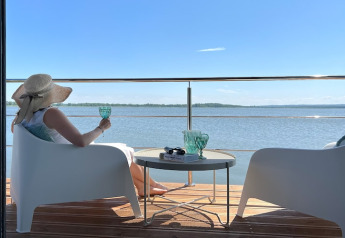 Woman relaxes on the houseboat 'House on the water for 2 people' in Denmark, enjoying the waterfront view.