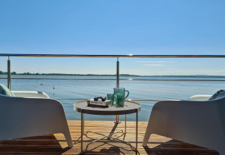 View from a houseboat in Denmark with two chairs, table, books and glasses overlooking the water.