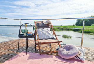 Cozy deck setup with chair, table, and water view at 'House on the water for 2 people' houseboat in Denmark.