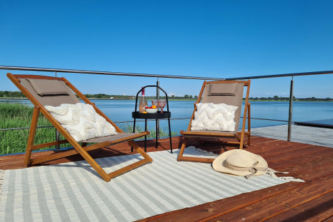 Ontspannende houseboat-terras met twee ligstoelen, kussens en prachtig meerzicht in Denemarken.