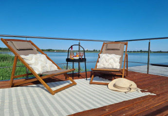 Ontspannende houseboat-terras met twee ligstoelen, kussens en prachtig meerzicht in Denemarken.