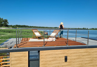 Vrouw geniet van het uitzicht op het dakterras van een woonboot voor 2 personen op een meer in Denemarken.