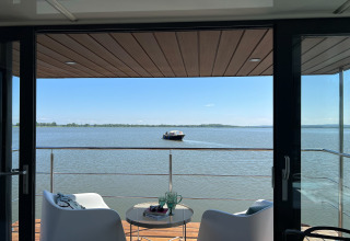 Uitzicht vanaf woonboot 'House on the water for 2 people' in Denemarken, terras met stoelen en boot op het meer.