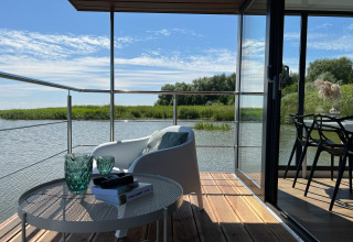 Uitzicht vanaf het terras van een woonboot in Denemarken met stoel en tafel over het water voor twee.