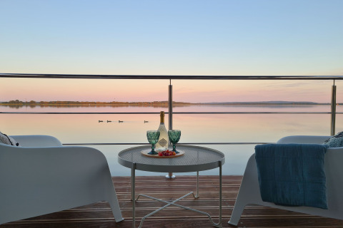 Uitzicht vanaf woonboot 'House on the water for 2 people' in Denemarken met wijn en rustig meer.
