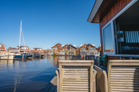 Vue depuis la péniche «Woude» à Marina Uitgeest aux Pays-Bas avec bateaux et maisons modernes.