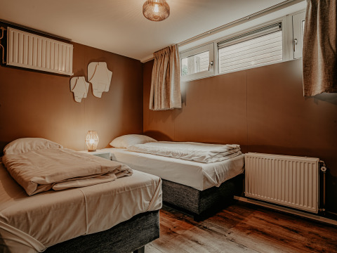 Camera da letto con due letti singoli, pareti marroni e grandi finestre sulla Houseboat «Woude» a Marina Uitgeest.