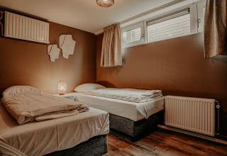 Soveværelse med to enkeltsenge, brune vægge og store vinduer på husbåden Houseboat «Woude» i Marina Uitgeest.
