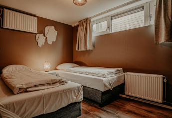 Camera da letto con due letti singoli, pareti marroni e grandi finestre sulla Houseboat «Woude» a Marina Uitgeest.