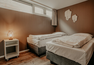 Modern bedroom on Houseboat «Woude» at Marina Uitgeest, Netherlands, with two single beds and warm lighting.