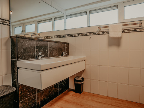 Baño moderno con doble lavabo, gran espejo, toallero y azulejos en blanco y negro en una casa flotante de Países Bajos.