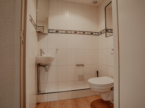 Modern houseboat bathroom at Marina Uitgeest, Netherlands, featuring a wall-mounted toilet and small sink.