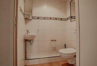 Moderne badkamer op woonboot in Marina Uitgeest, Nederland, met zwevend toilet en klein wasbakje.