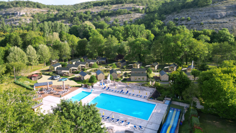 Aerial view of Dordogne Deluxe at La Draille in France, featuring a pool, lodges, and lush green forest.