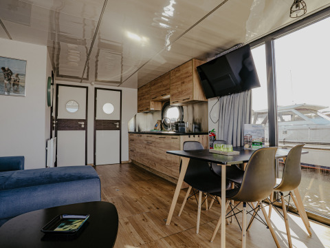 Moderne leefruimte en keuken op woonboot 'Campi' aan Marina Uitgeest, Nederland, met zicht op de jachthaven.