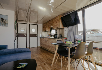 Modernes Wohnzimmer und Küche im Hausboot 'Campi' in der Marina Uitgeest, Niederlande, mit Hafenblick.