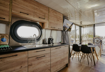 Moderne woonboot Campi bij Marina Uitgeest, keuken en eettafel met groot raam en zicht op het water.