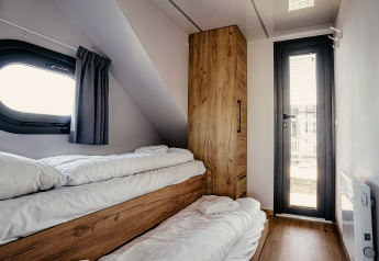 Gezellige slaapkamer met stapelbedden en houten kast op woonboot «Campi» bij Marina Uitgeest, Nederland.