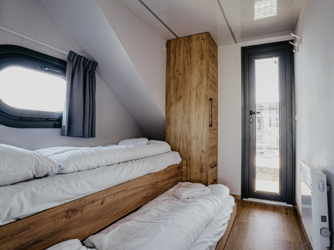 Accogliente camera da letto con letti a castello e armadio in legno sulla houseboat «Campi» a Marina Uitgeest.